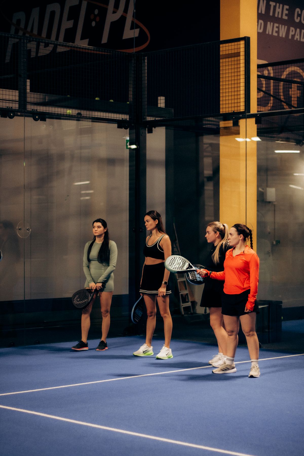 Vier padelspeelsters samen op een indoor padelbaan