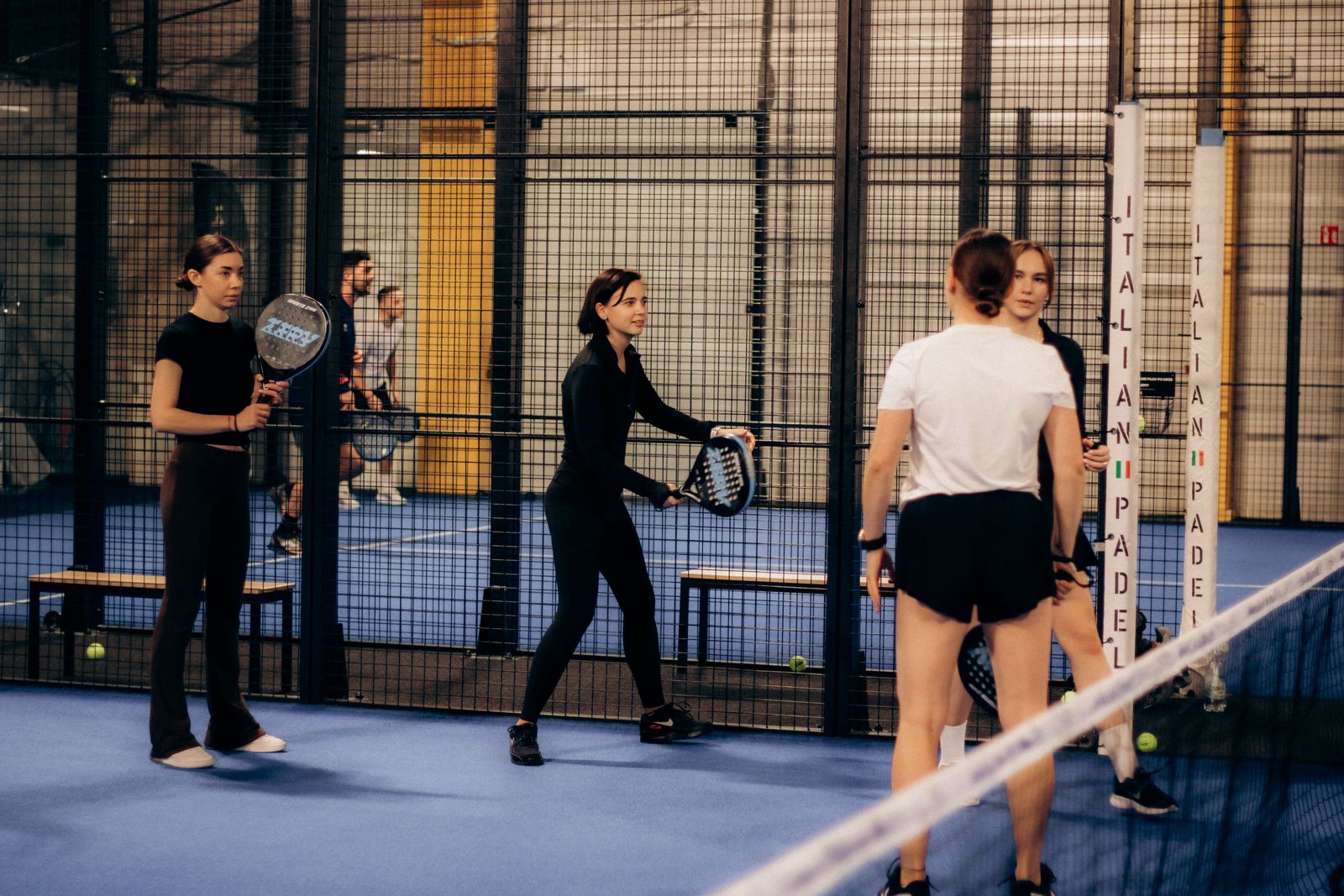 Vier padelspelers samen op een moderne indoor padelbaan