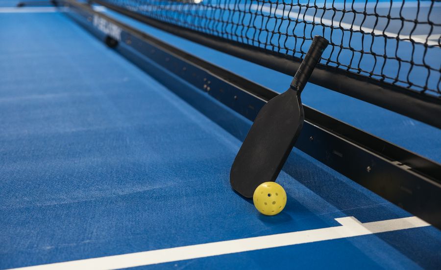 Pickleballbat en bal op een blauwe baan